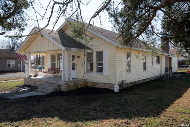 exterior space with a porch, a front yard, a shingled roof, and central air condition unit