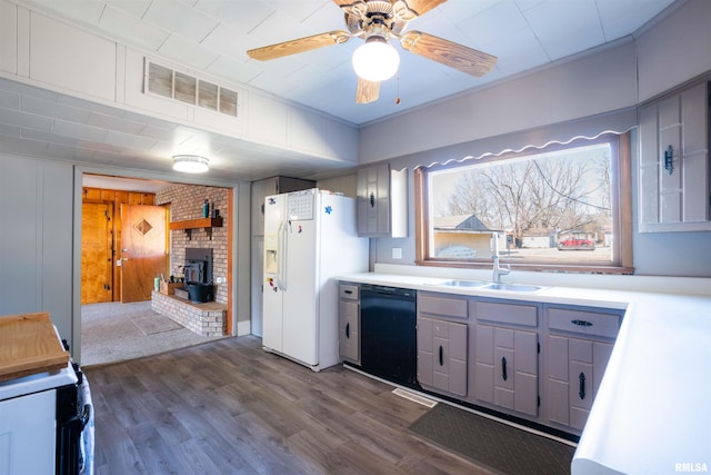 kitchen with white refrigerator with ice dispenser, visible vents, a wood stove, a sink, and dishwasher