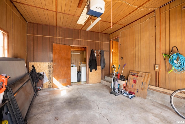 garage featuring a garage door opener, washing machine and dryer, and wood walls