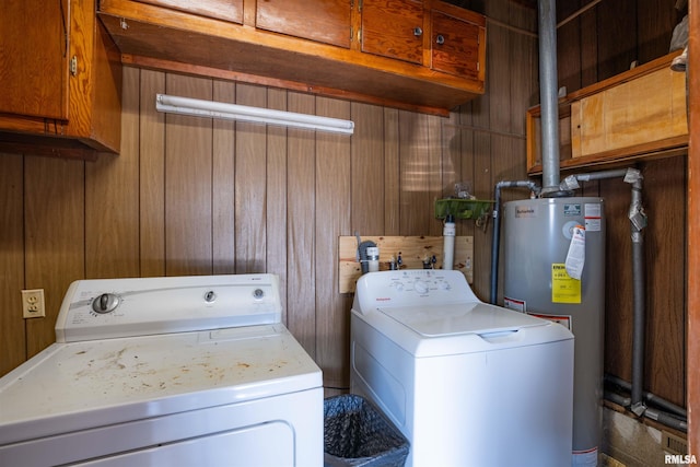 laundry room with cabinet space, wooden walls, water heater, and washing machine and clothes dryer