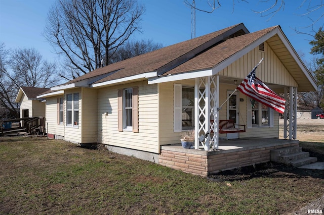 view of property exterior featuring covered porch, a lawn, and roof with shingles