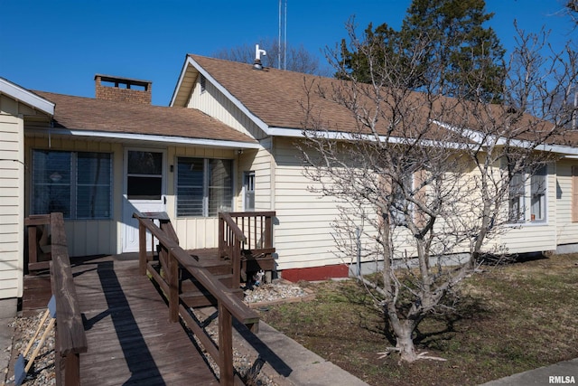 view of front facade featuring roof with shingles and a chimney