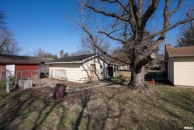 exterior space featuring a chimney, a lawn, and an outbuilding