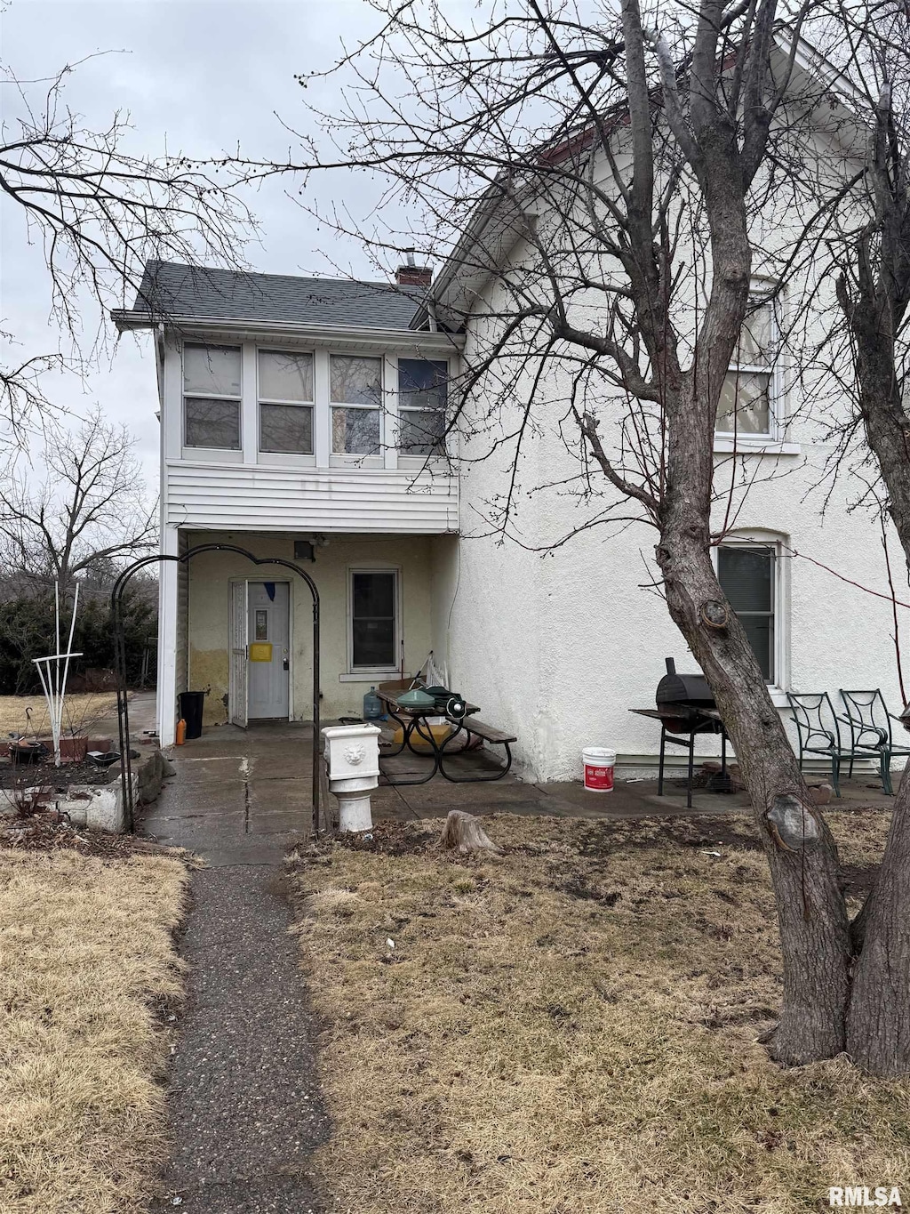 view of front of home featuring a chimney, a patio area, and stucco siding