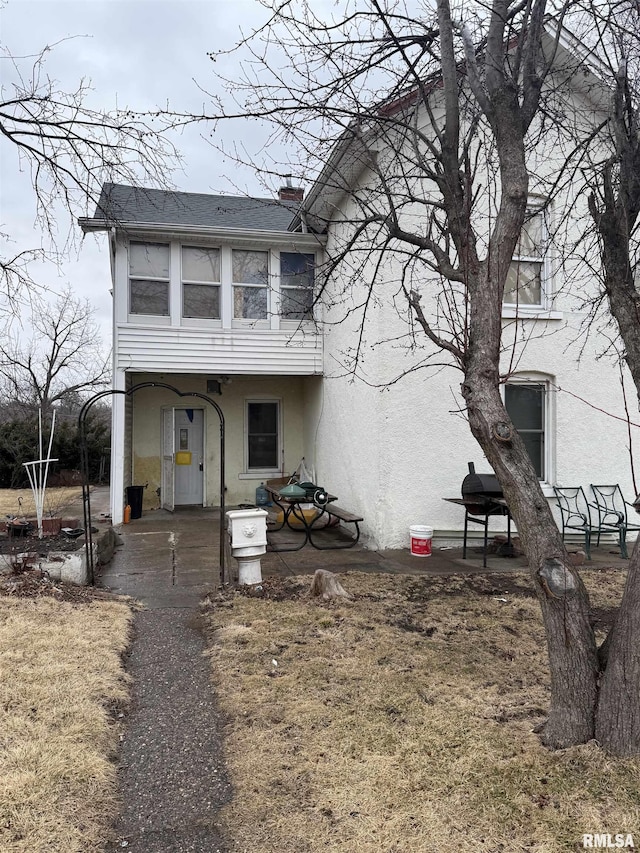 view of front of home featuring a chimney, a patio area, and stucco siding