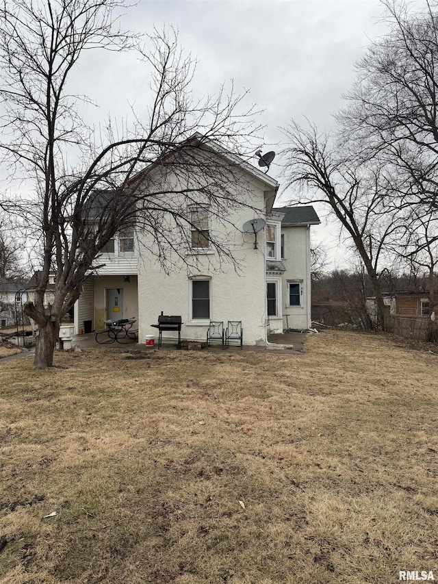 back of property with a patio area, a lawn, and stucco siding