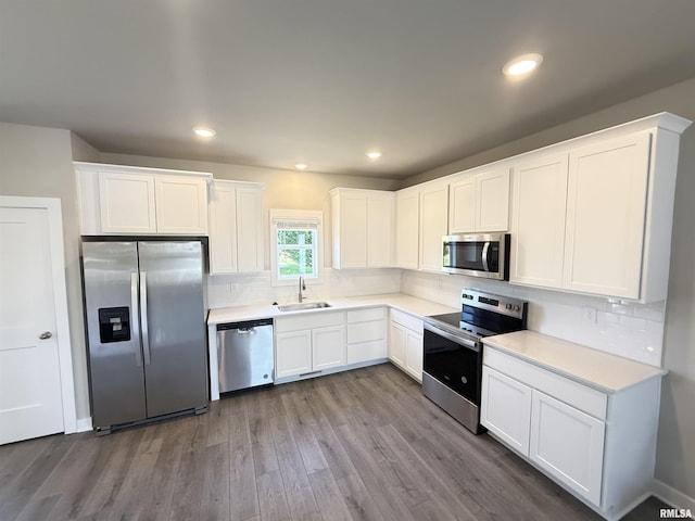 1631 Westport Dr, Davenport, IA 52804 - kitchen featuring appliances with stainless steel finishes, wood finished floors, white cabinetry, tasteful backsplash, and recessed lighting