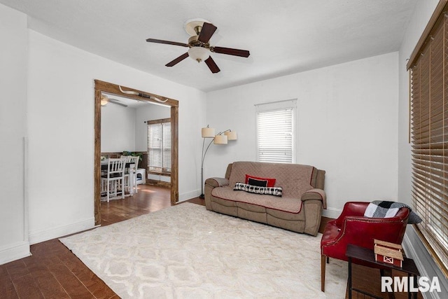 living room featuring a ceiling fan, a wealth of natural light, baseboards, and wood finished floors