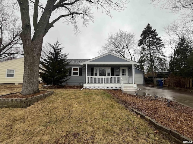 view of front of home with a front yard, covered porch, and driveway