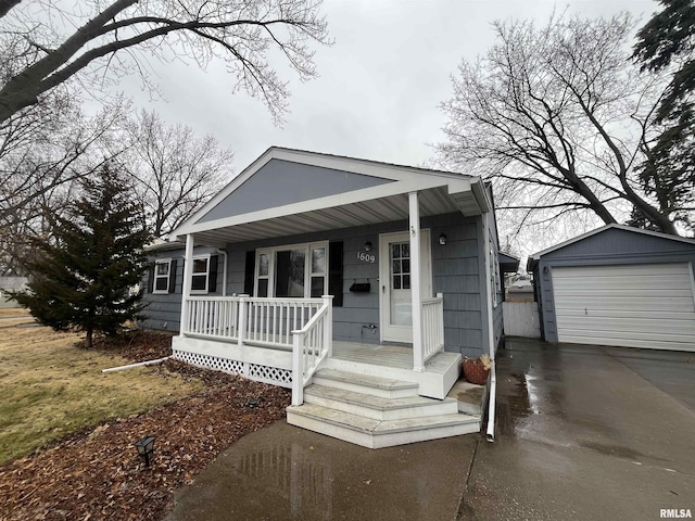 view of front of property with a detached garage, a porch, concrete driveway, and an outdoor structure