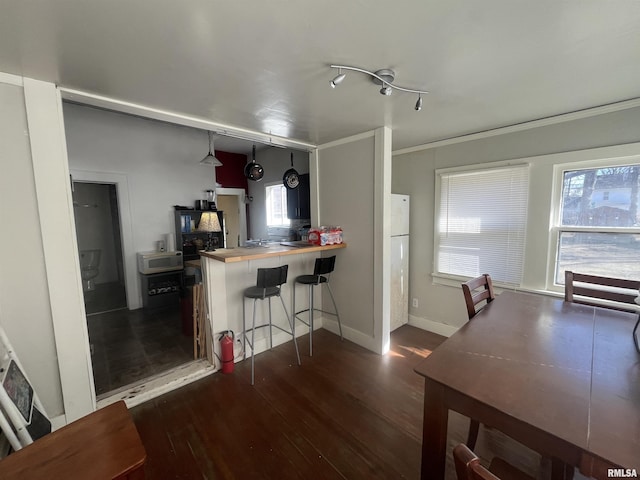 kitchen featuring a kitchen breakfast bar, crown molding, baseboards, and wood finished floors