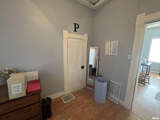 interior space featuring a high ceiling, wood finished floors, visible vents, and baseboards