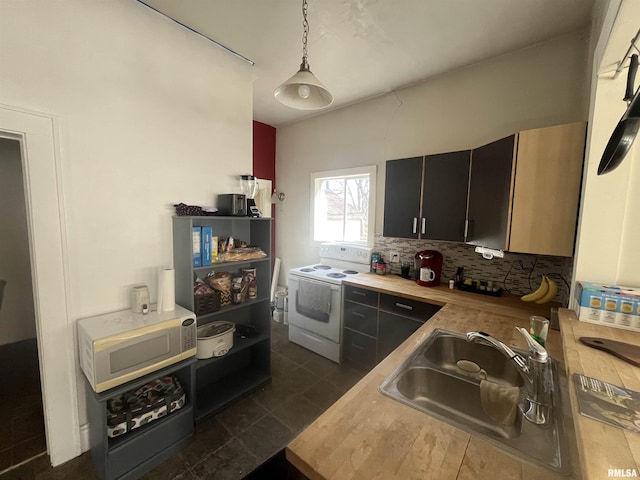 kitchen with dark cabinets, white appliances, a sink, backsplash, and decorative light fixtures