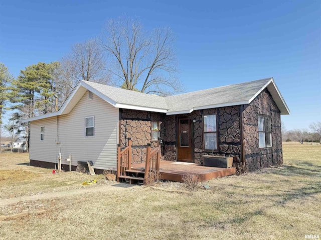 exterior space featuring stone siding, a front lawn, and a wooden deck