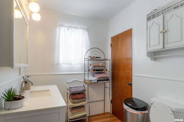 bathroom with wainscoting, tile walls, toilet, and vanity