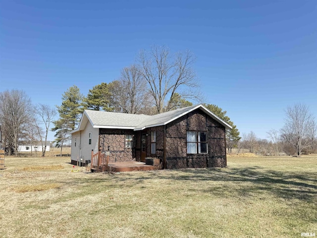 view of side of home with stone siding and a yard