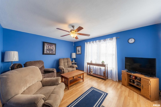 living area featuring a ceiling fan, a textured ceiling, and wood finished floors