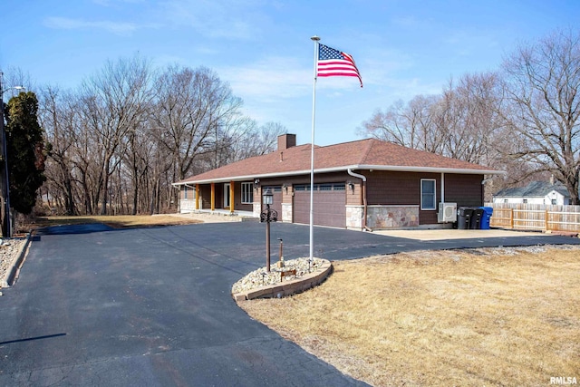 single story home with a chimney, fence, a garage, stone siding, and driveway