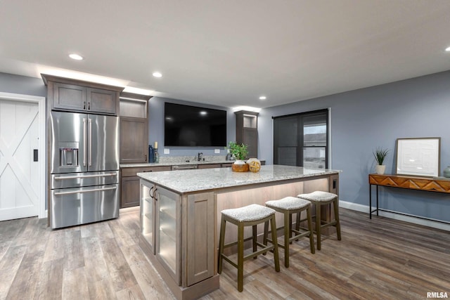 kitchen featuring wood finished floors, high end refrigerator, a kitchen island, and recessed lighting