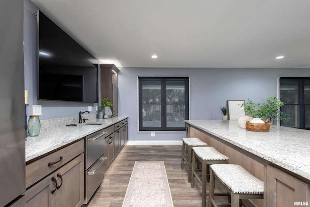 kitchen featuring a warming drawer, a breakfast bar area, recessed lighting, dark wood-type flooring, and light stone countertops