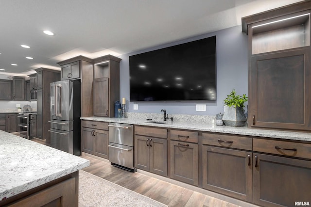 kitchen featuring stainless steel appliances, recessed lighting, a sink, and light wood finished floors