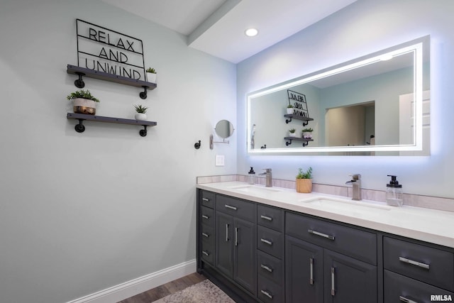 bathroom featuring double vanity, wood finished floors, a sink, and baseboards