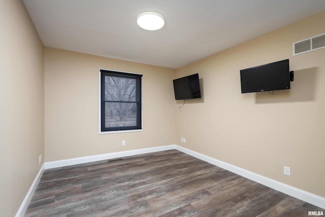 unfurnished room featuring baseboards, visible vents, and dark wood-type flooring