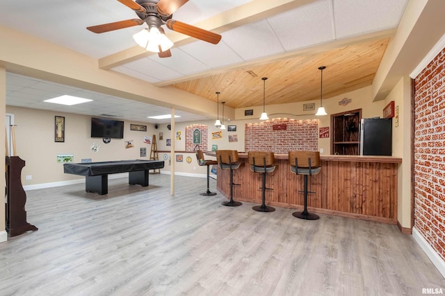 interior space featuring baseboards, wood finished floors, indoor wet bar, and freestanding refrigerator