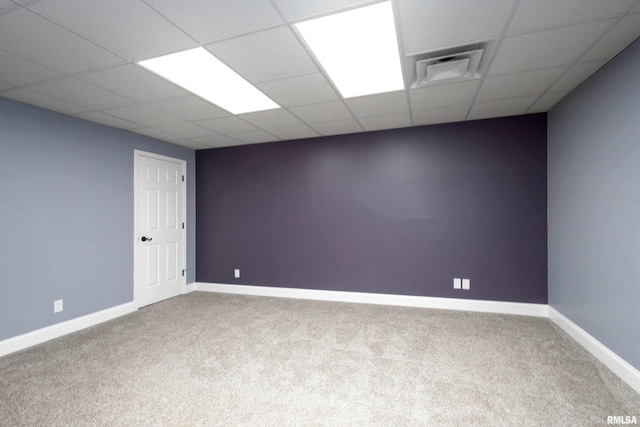 carpeted empty room featuring a paneled ceiling, visible vents, and baseboards