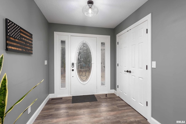 foyer with baseboards and dark wood-style flooring