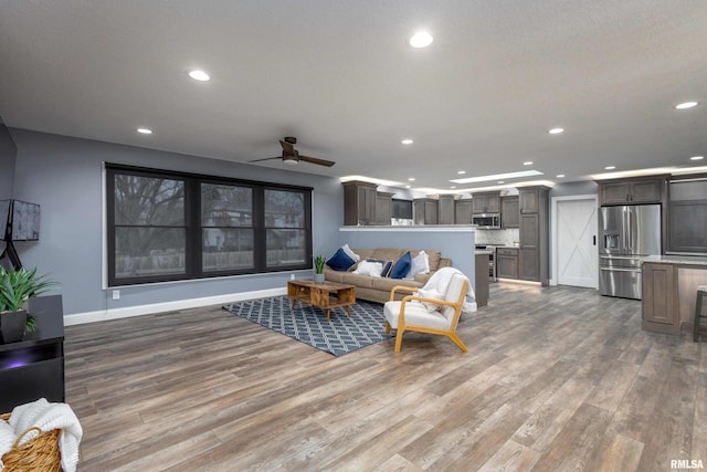 living area featuring ceiling fan, baseboards, wood finished floors, and recessed lighting