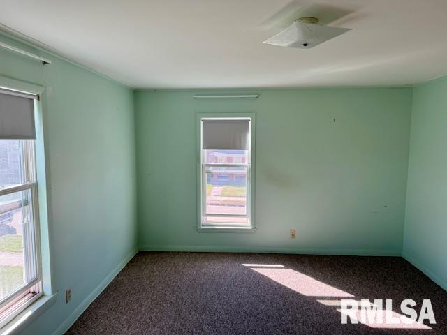 unfurnished room featuring carpet and baseboards