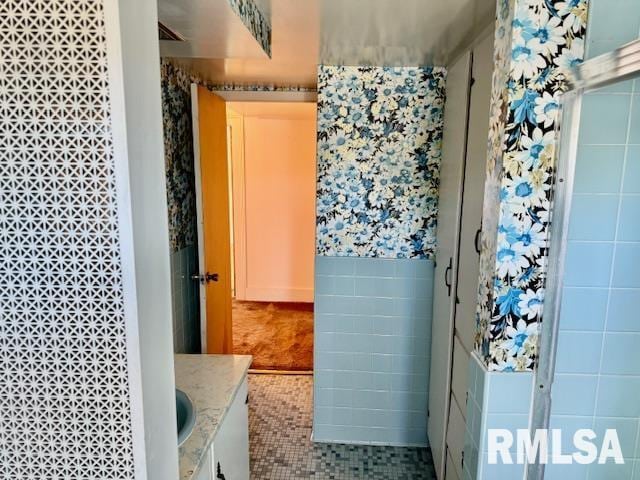 bathroom with a shower, tile walls, vanity, and tile patterned floors