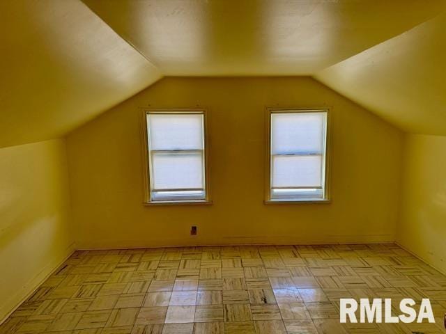 additional living space with lofted ceiling, a healthy amount of sunlight, and baseboards