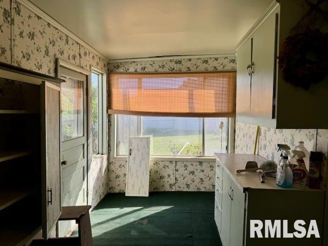 interior space featuring wallpapered walls, dark carpet, and light countertops