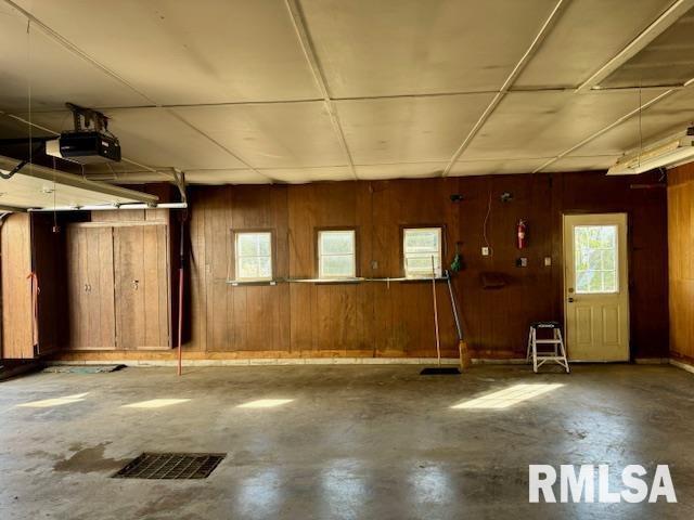 garage with wood walls, visible vents, and a garage door opener