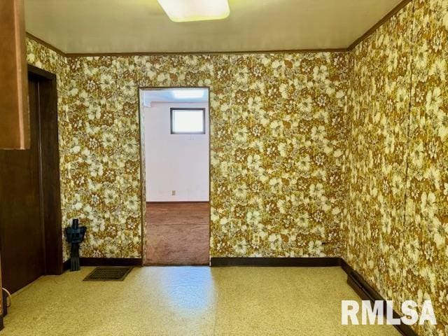 empty room with ornamental molding, visible vents, and baseboards