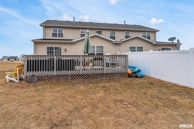 rear view of house with a wooden deck, fence, and a yard