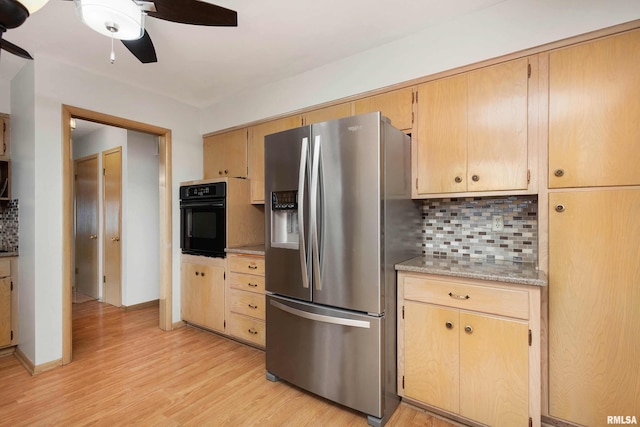 kitchen with light wood-style flooring, oven, stainless steel fridge, and backsplash