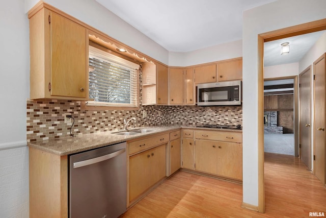 kitchen featuring light wood finished floors, appliances with stainless steel finishes, decorative backsplash, and a sink