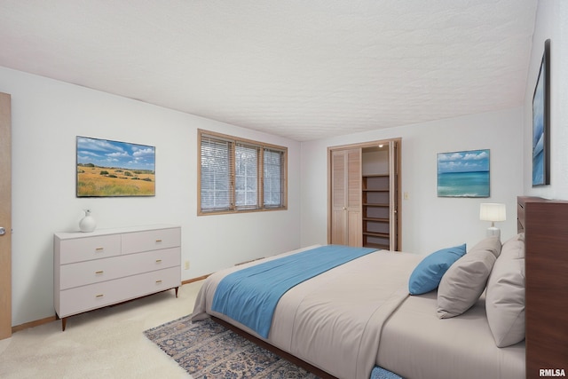 bedroom featuring baseboards, a textured ceiling, a closet, and light colored carpet