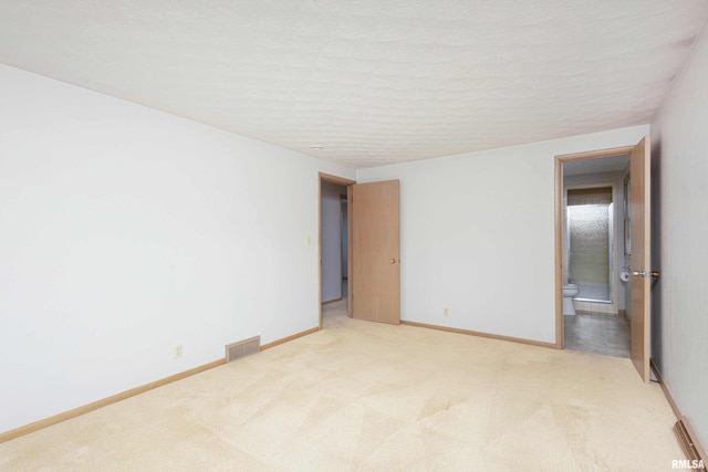 spare room featuring baseboards, visible vents, a textured ceiling, and light colored carpet