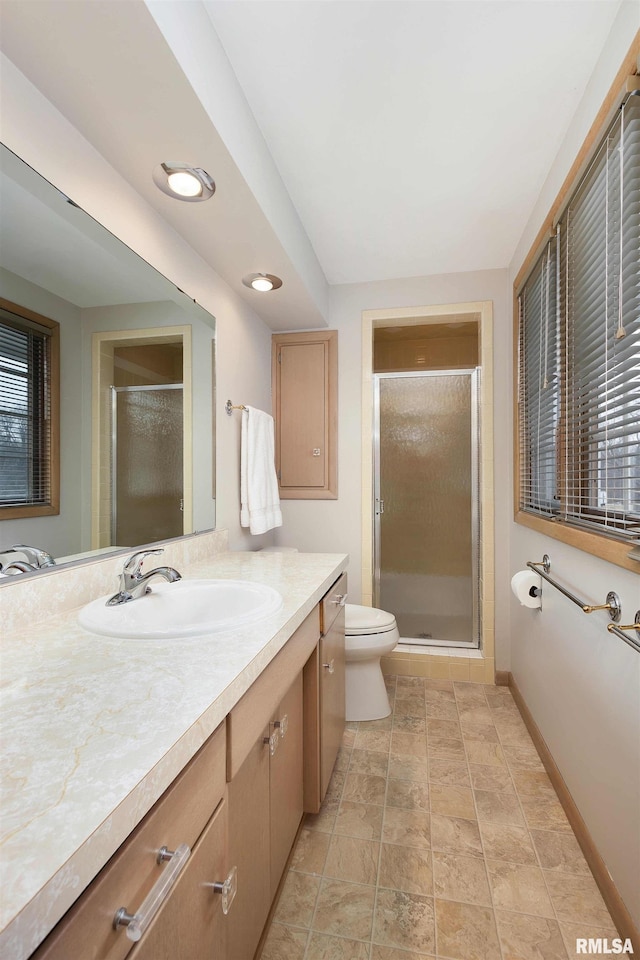 bathroom with baseboards, toilet, a shower stall, and vanity