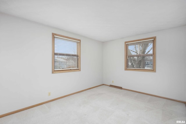 unfurnished room featuring light carpet, plenty of natural light, and baseboards