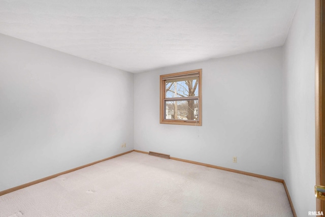 empty room featuring light carpet and baseboards