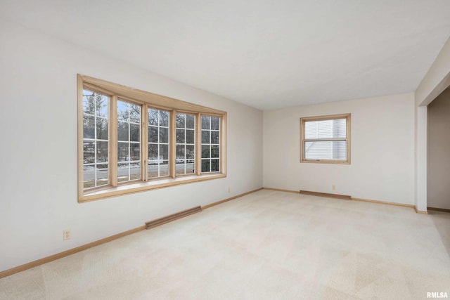 spare room featuring light carpet, visible vents, and baseboards