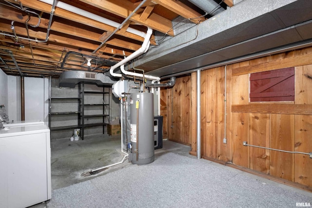 unfinished below grade area featuring washer / dryer, wooden walls, and gas water heater