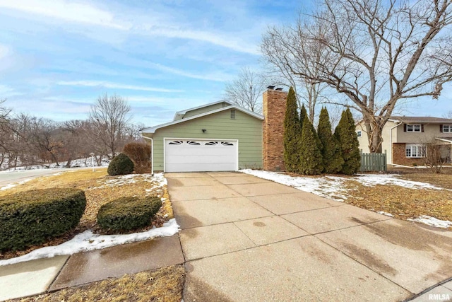 view of home's exterior featuring a garage, a chimney, and fence