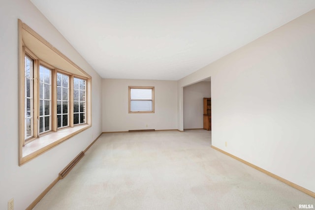 unfurnished room featuring light carpet and baseboards