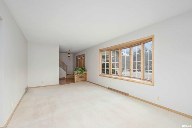 unfurnished room featuring stairs, carpet flooring, visible vents, and baseboards